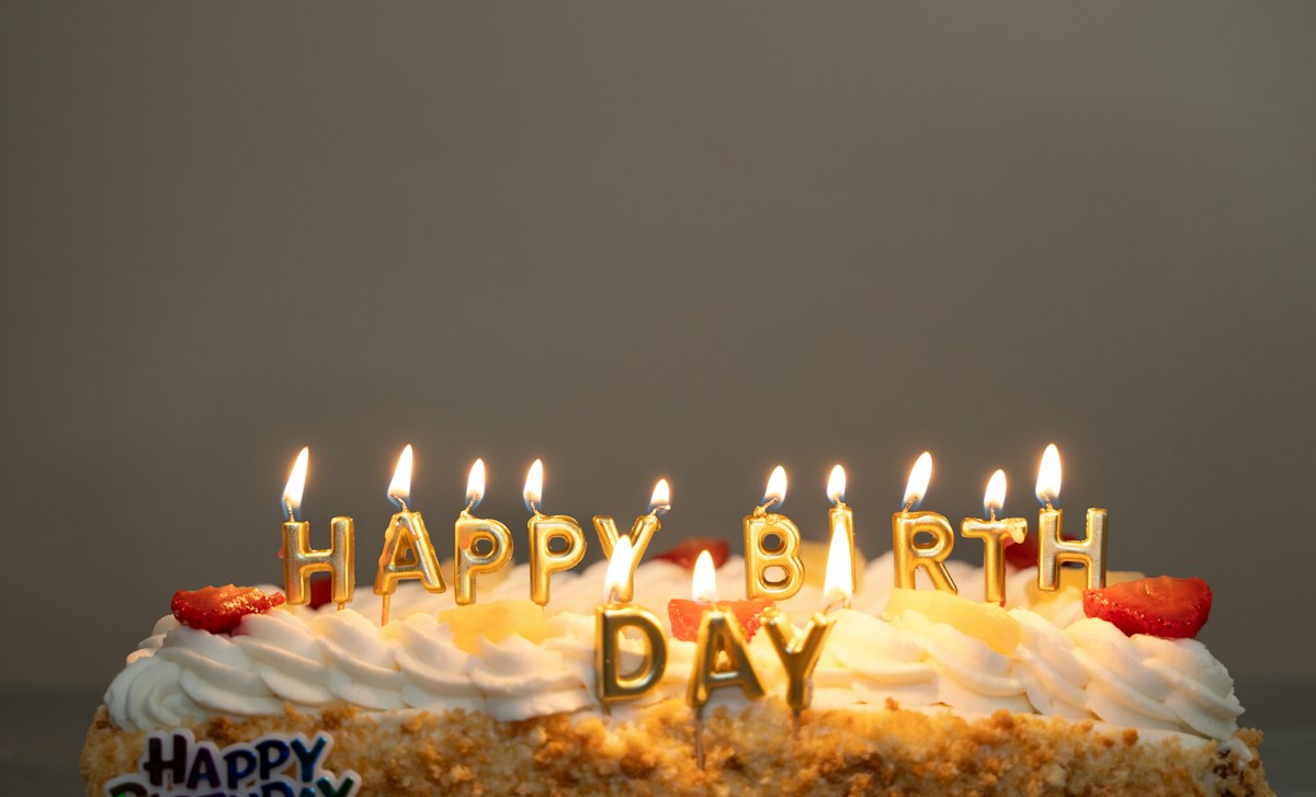 White birthday cake with lit candles